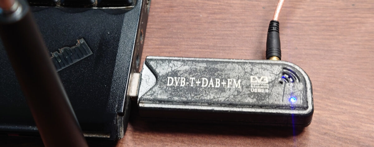 A DVB-T stick plugged into a laptop, resting on a desk.